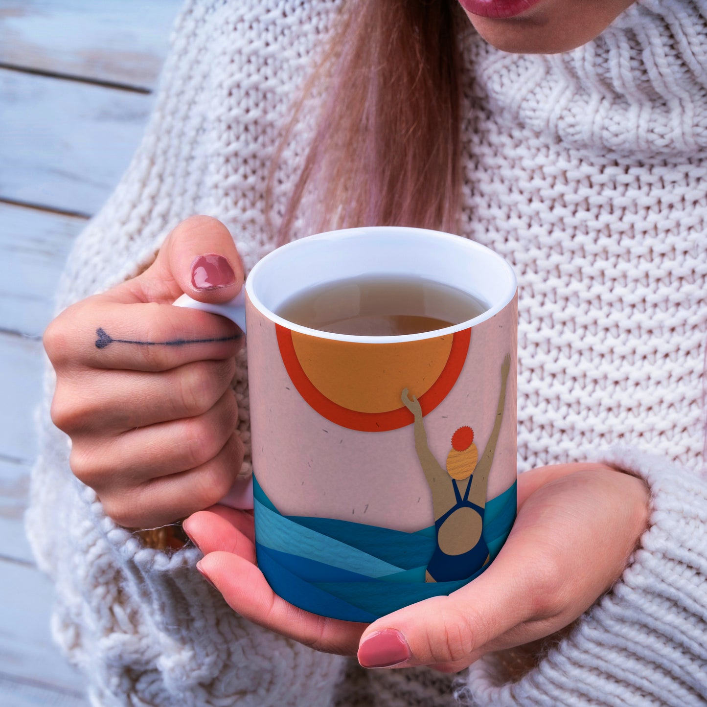 Women holding a mug with a design of a wild swimmer jumping for joy in the sea.